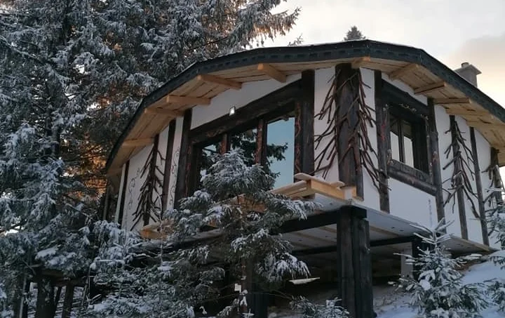 Casuta Con, o casă unică din lemn, cu un design tradițional, acoperită de zăpadă, oferind o experiență autentică de cazare rurală în iarnă.