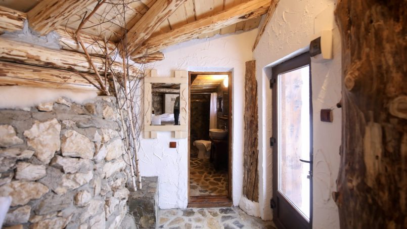 Interior rustic cu perete din piatră, cadru din lemn și decor natural