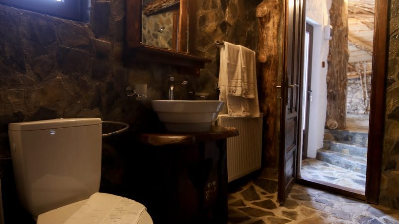 Băie rustică cu podea din piatră, tavan din lemn și mobilier simplu