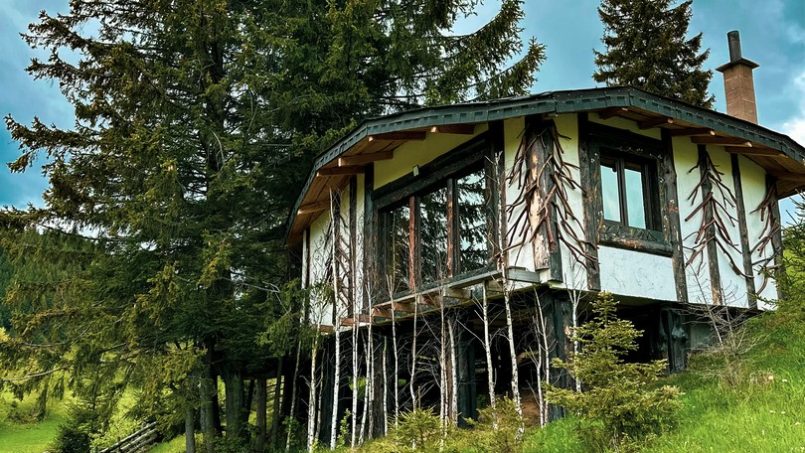 Casuta Con - exterior panoramic din alt unghi, casă modernă cu design unic și zonă jardiniere într-un mediu rural pitoresc