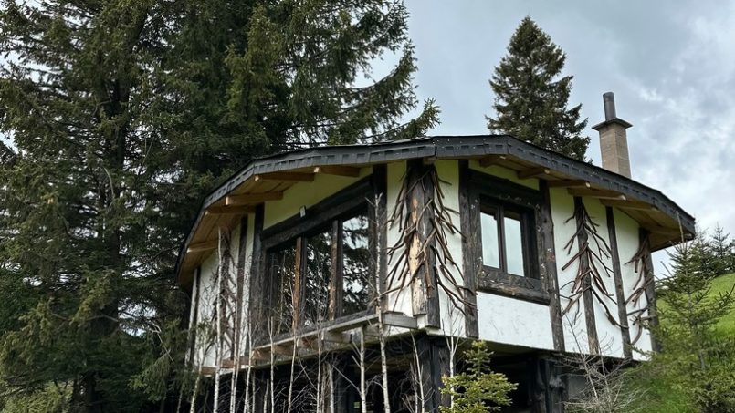 Casuta Con - exterior panoramic din alt unghi, casă modernă cu design unic și zonă jardiniere într-un mediu rural pitoresc