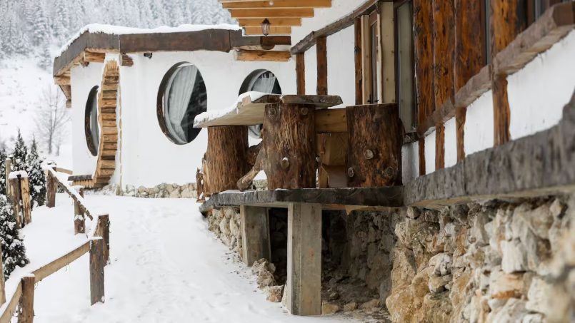 Rustic winter cottage exterior with wooden accents and snow-covered landscape