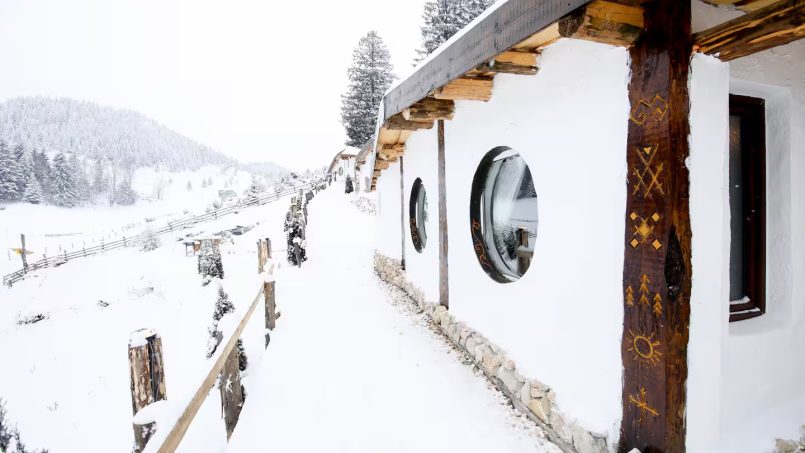 Snowy cottage with decorative woodwork and scenic mountain views