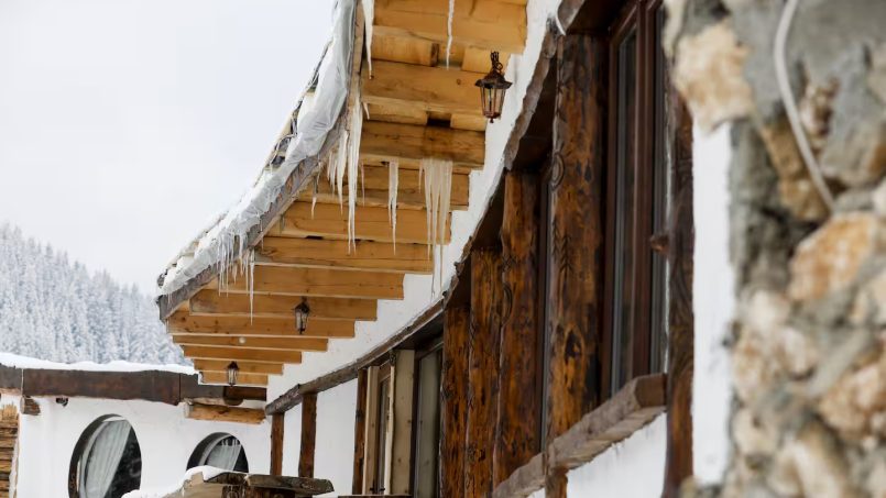Winter cottage roof with icicles hanging from the eaves